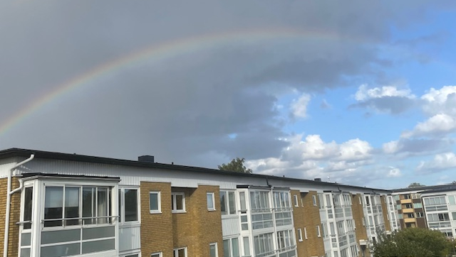 Bild på föreningens hus med en regnbåge ovanför